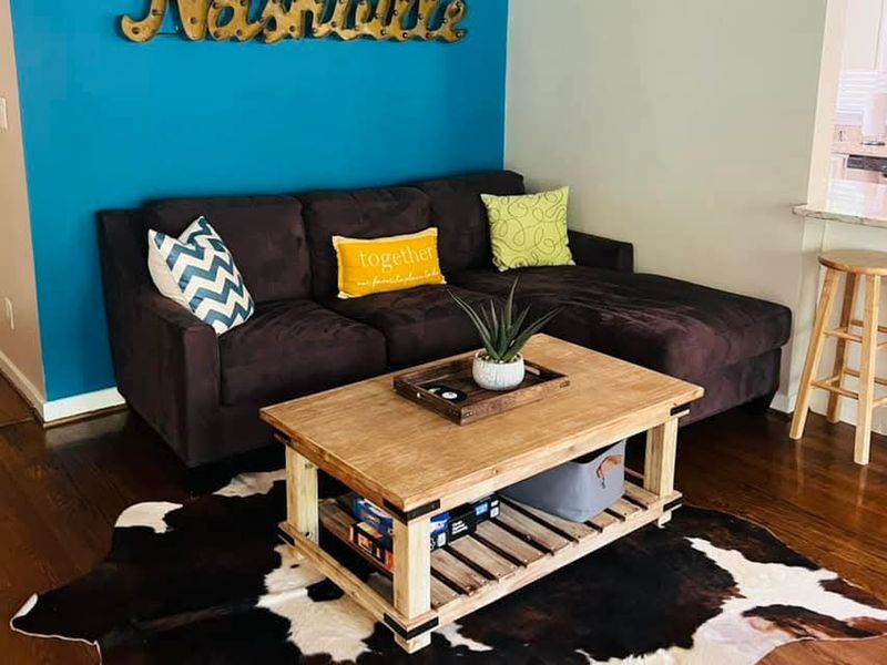 Short-term rental living room with navy sofa, cowhide rug, and Nashville sign, cleaned and staged