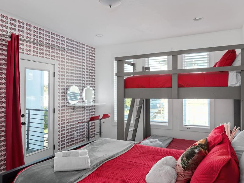 Bunk room with red bedding and made beds after a short-term rental turnover