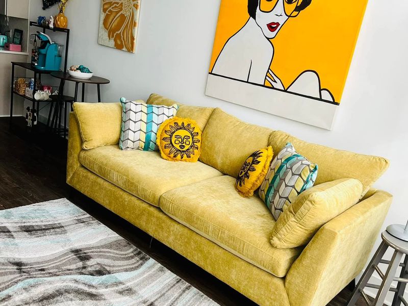 Bright living room with yellow sofa and patterned rug, cleaned for the next guest