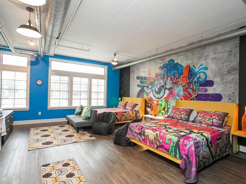 Colorful loft bedroom with mural wall and freshly made bed in a Middle Tennessee rental