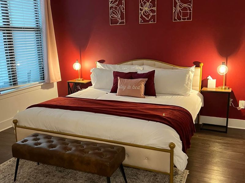 Bedroom with red accent wall, crisp white linens, and bench, staged after a turnover