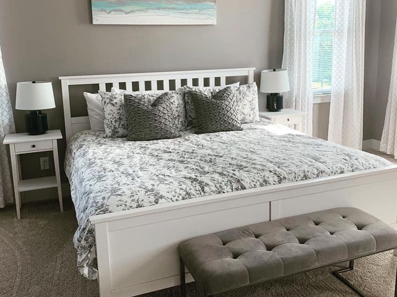 Guest bedroom with patterned bedding and upholstered bench after professional cleaning